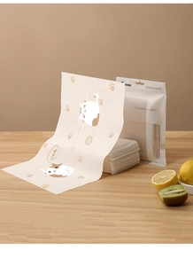 Close-up of disposable cat pattern placemat with OOKII packaging on a wooden table