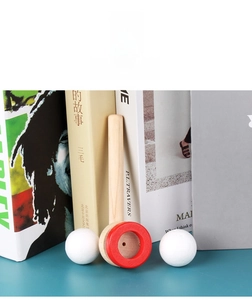 Detail of wooden breath trainer toy with red ring and white foam balls on a teal desk