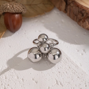 Macro shot of silver geometric ring with metal spheres on a textured stone surface
