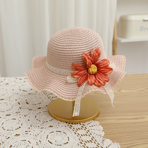 Détail d'un chapeau en paille rose avec tournesol orange et bordure en dentelle