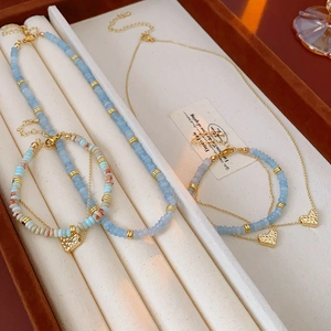 Detail view of light blue Shoushan stone beads and golden heart charms on jewelry set