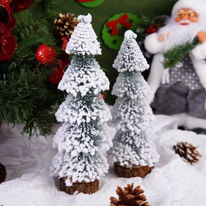 Close-up of mini snow-flocked Christmas trees with natural wood bases for table decor