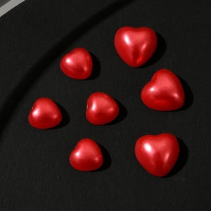 Close-up of pearl-finish red heart beads in various sizes for nail art and crafts