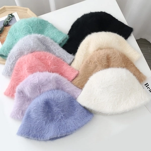 Flat lay of multiple fuzzy faux fur bucket hats in various colors with plush texture
