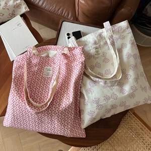 Détail du sac cabas en toile avec motif nœud rouge sur une table en bois d'un salon