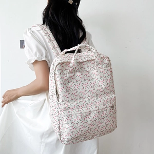 Floral canvas backpack with pink flower patterns worn by a model against a white wall