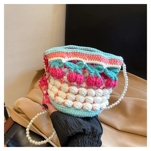 Detail showing hand-crocheted bucket bag with popcorn stitch texture and pearl strap