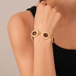 Detail of vintage gold bracelet with red gemstones and delicate white flower patterns