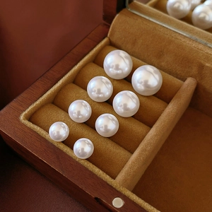 Detailed view of graduated white pearl stud earrings set in a premium velvet wooden box