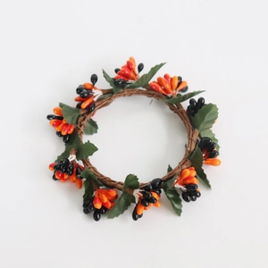 Macro detail of artificial harvest candle ring with orange and black pips for fall decor