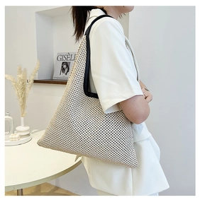 Close-up of beige woven tote bag with black handles in a minimalist home setting