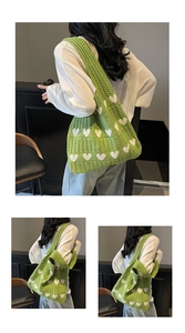 Detalle del bolso de hombro de punto verde con patrón de corazón blanco y tejido hueco