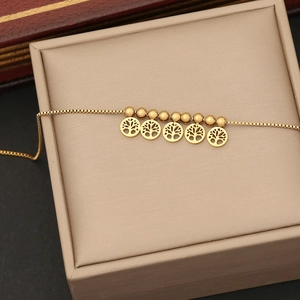 Detailed shot of a gold beaded bracelet featuring five Tree of Life hollow charms on a box chain