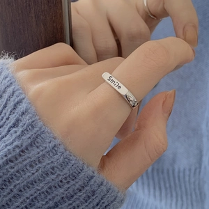 Macro detail of silver Smile engraved adjustable open ring with polished metal texture