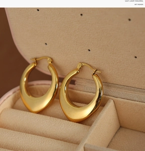 Macro detail of thick 18K gold plated U-shaped drop earrings with a polished mirror finish