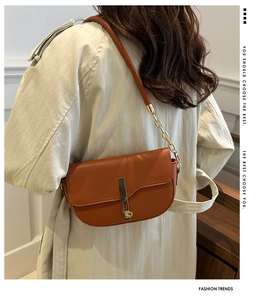 Detail of dark brown saddle bag with lychee pattern leather and gold metal buckle