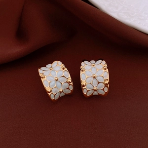Macro shot of 18k gold-plated C-shape earrings with white enamel flower petals