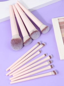 Close-up of 13 professional makeup brushes with pink matte handles and gradient bristles