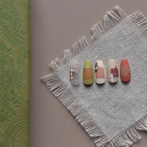 Detailed view of vintage nail art tips with retro fabric texture and pearl embellishments