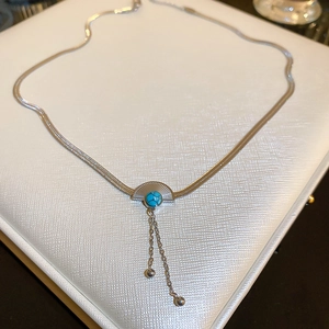 Macro detail of snake chain and fan pendant with blue turquoise stone and tassels