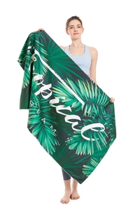 Model holding a full-size microfiber beach towel with tropical palm leaves and Smile text