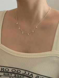 Close-up of minimalist silver zircon necklace with six round pendants on a model