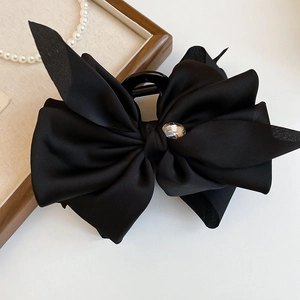 Detailed view of a large black satin bow hair claw clip with a sparkling crystal center