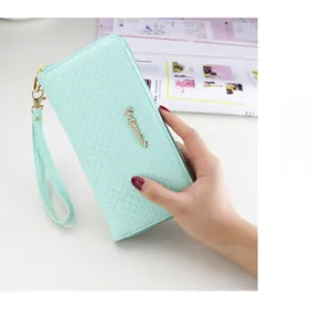 Detail of mint green cross-grain leather wallet with wrist strap and gold metal hardware