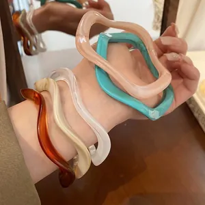 Stack of colorful resin bangles with irregular wave design in amber and pastel shades