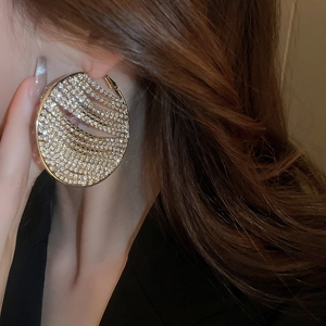 Close-up of luxury oversized gold hoop earrings with sparkling rhinestones on model