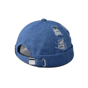 Detail of distressed denim docker cap with ripped accents and metal buckle strap