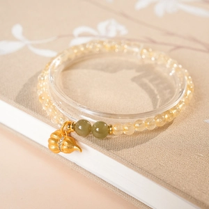 Nahaufnahme gelbes Perlenarmband mit grünen Akzenten und mattgoldenem Gourd-Anhänger
