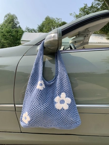 Detail der himmelblauen Stricktasche mit weißen Blumenmustern am Autospiegel