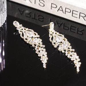 Close-up of sparkling rhinestone teardrop tassel earrings on a black reflective surface