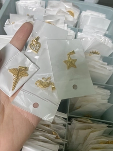 Detail of assorted gold unicorn and sun god steel pendants in transparent packaging