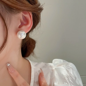 Close-up of a large white round pearl earring worn on the ear for a stylish look