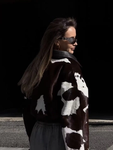 Detailed close-up of cow print faux fur jacket featuring a black faux leather collar