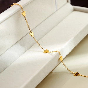 Macro shot of gold butterfly charms on a polished delicate chain over white velvet