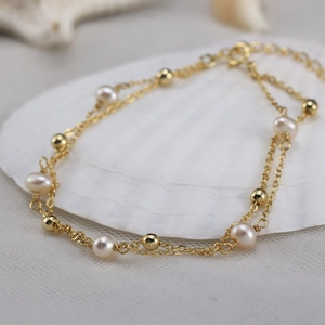 Double-layered gold bracelet featuring natural freshwater pearls and polished metal beads