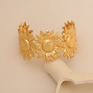 Détail d'un bracelet jonc tournesol doré ajustable sur un présentoir esthétique blanc