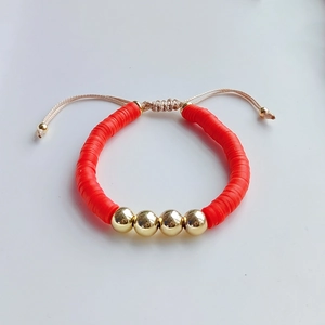 Detail of red heishi bead bracelet with gold metal accents and adjustable drawstring cord