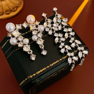 Detailed shot of silver leaf earrings with pearls and crystals on a luxury black jewelry box