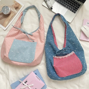 Close-up of bow knot fabric bags in pink plaid and navy blue patterns on a bed
