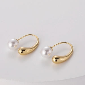 Macro detail of French retro gold plated C-shape earrings with a large white freshwater pearl