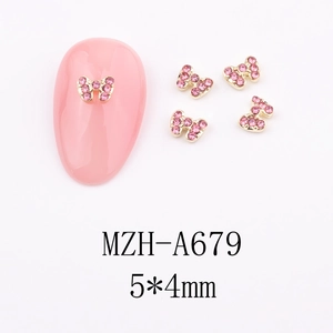 Macro view of 5x4mm bow-shaped nail charms with gold base and pink rhinestones