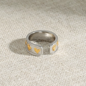 Gros plan détaillé d'une bague cœur bicolore en acier inoxydable sur lin beige