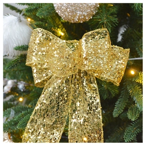Detail of champagne gold sequined bow topper on green Christmas tree branch