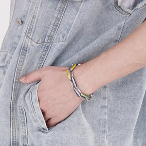 Detail of colorful enamel Cuban link bracelet on a male model wearing denim jeans