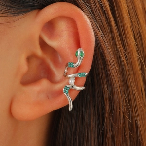 Macro di un ear cuff a serpente argento con cristalli verdi e perla sull'orecchio