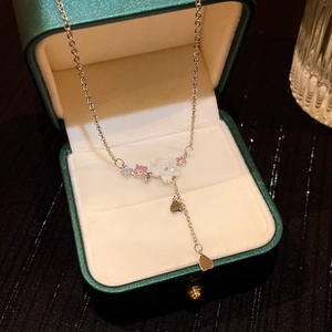 Detail of silver floral necklace with pink crystals and pear-shaped drop in a green gift box